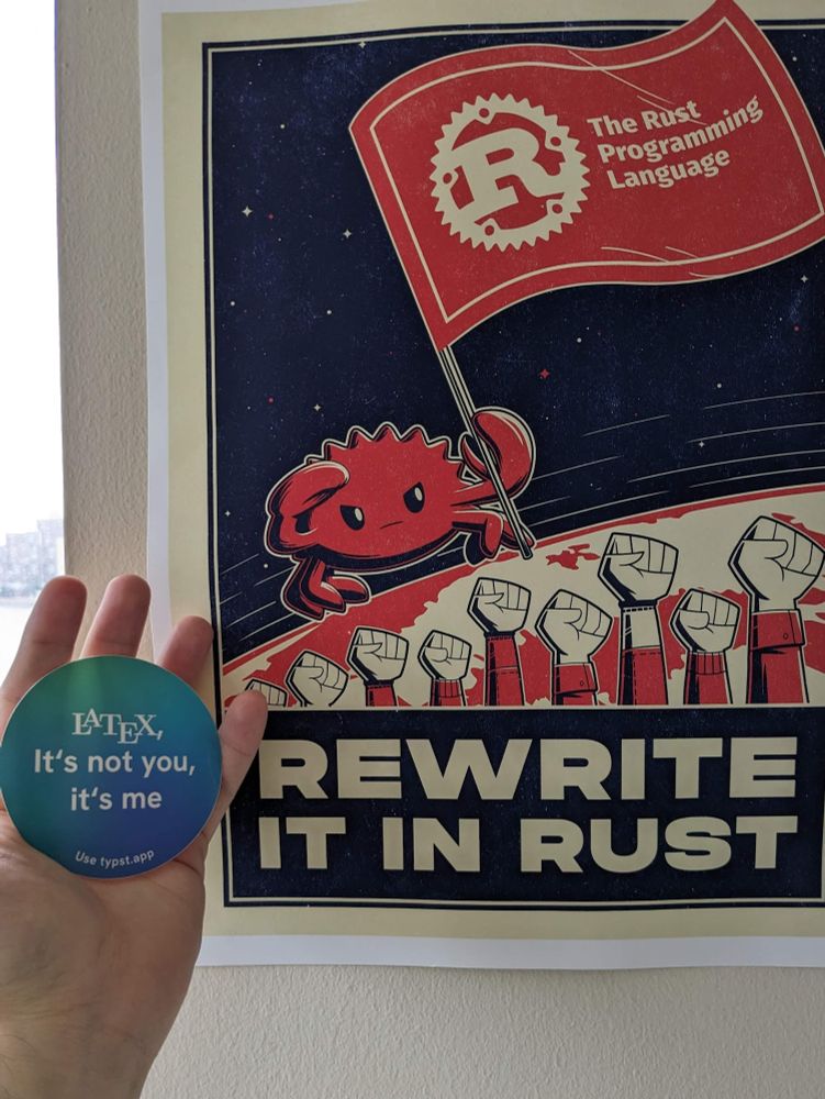 A typst sticker stating "LaTeX, it's not you - it's me" next to a poster with a red crab holding a flag of The Rust Programming Language and stating "Rewrite it in Rust"