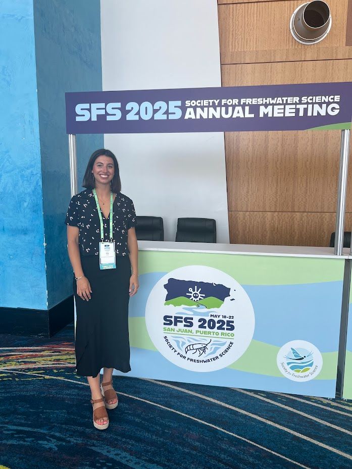 Elly is pictured in front of the Society for Freshwater Science booth