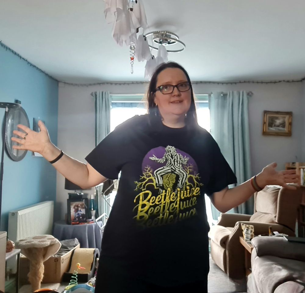 User @thequalmpeddler.bsky.social wears a Beetlejuice t-shirt and does the jazz hands like the main character does in the movie.