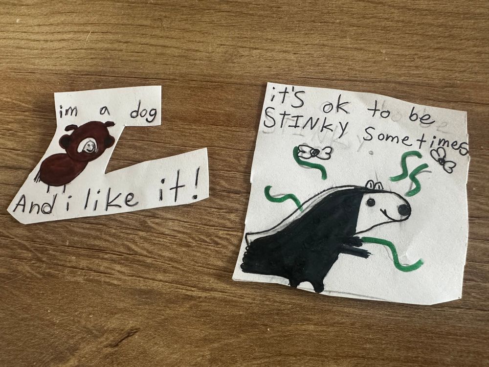 pair of child’s drawings of animals. one is of a brown dog and reads “i’m a dog and i like it!” the second reads “it’s ok to be stinky sometimes” and features a black bear with stink lines and flies surrounding him. 
