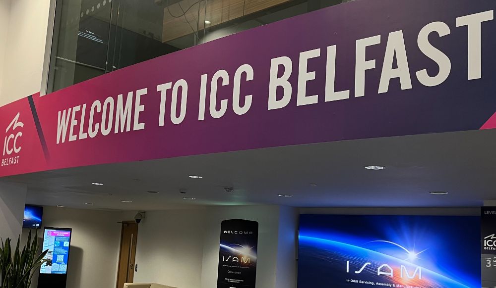 Banner reading "Welcome to ICC Belfast" displayed at the entrance of the convention centre, with additional signage and digital screens visible in the background.