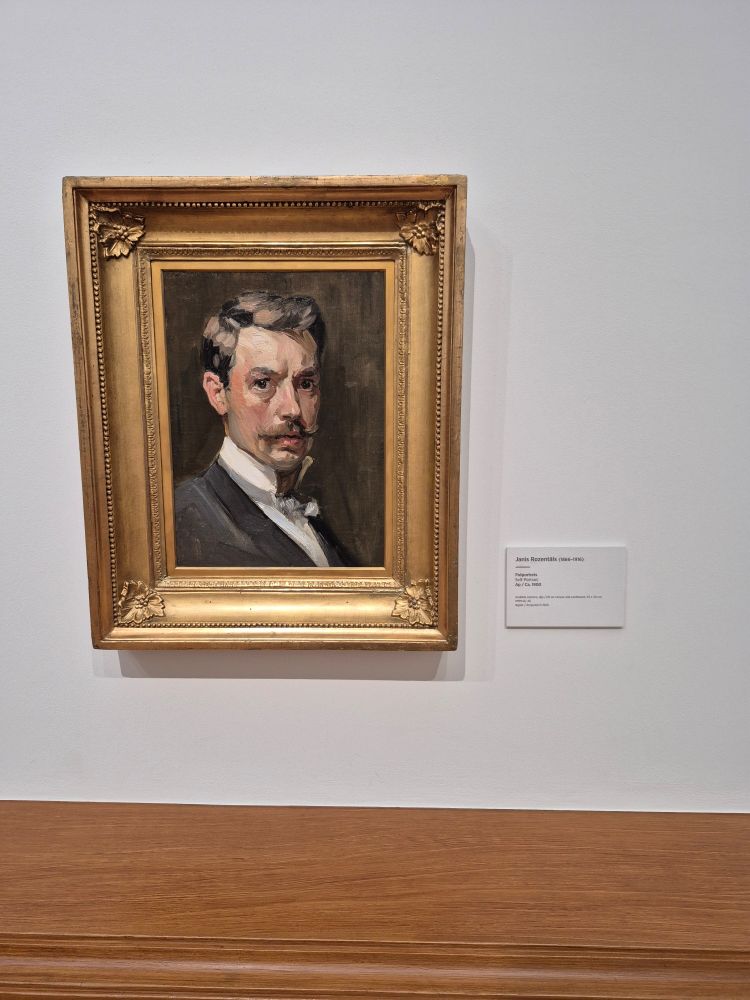 A self portrait in a gold frame, looking out at the viewer, in an impressionistic style
