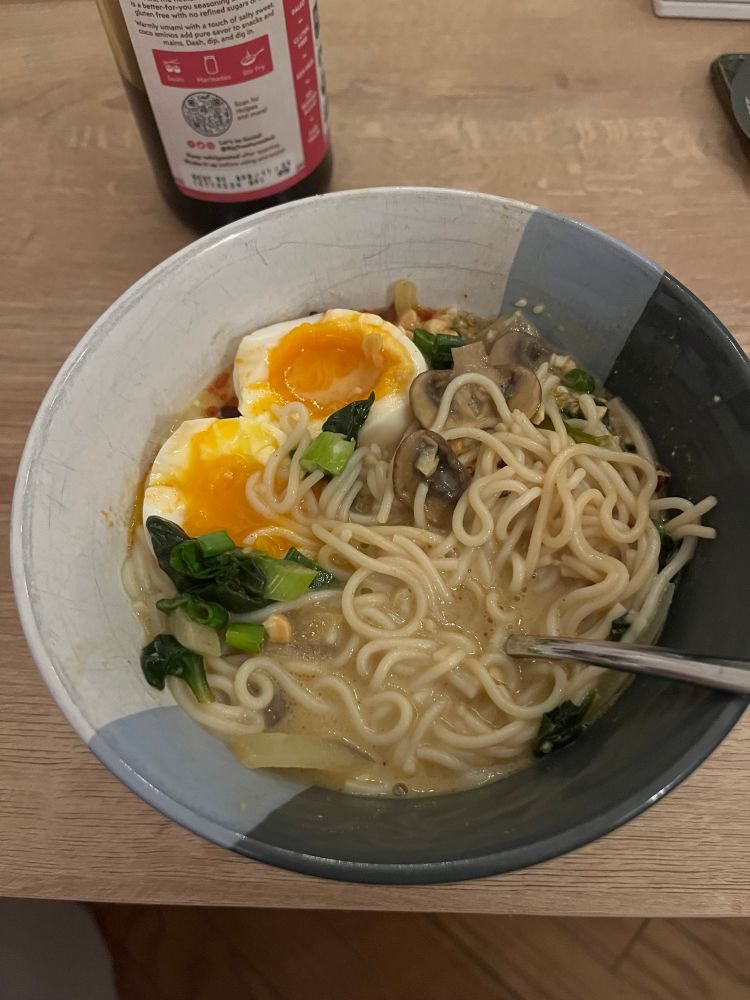 a bowl of peanut ramen with soft boiled eggs and scallions.  