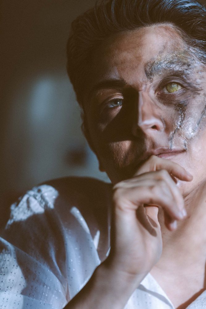 Closer shot of Silco. He now wears a smirk on his face, has stopped bothering with his work and is instead staring at his husband who is out of frame.