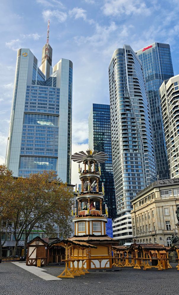 Commerzbank und Deka Bank Tower in Frankfurt. Im Vordergrund wird ein Weihnachtsmarkt auf dem Rossmarkt aufgebaut und eine vierstöckige Weihnachtspyramide mit kleinen Ständen aus Holz. 