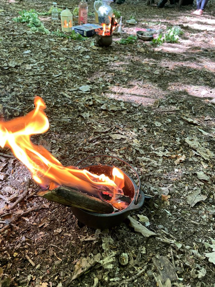 Bealtaine fire burns safely in a small cast-iron cauldron on the woodland floor 
