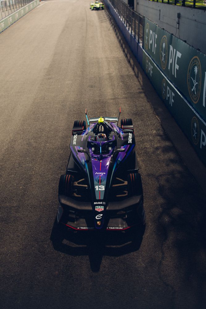 The purple Porsche of Antonio Felix Dacosta photographed from overhead as he accelerates underneath the camera. A strong shadow from the front nose cone is cast on the ground in front of the car.