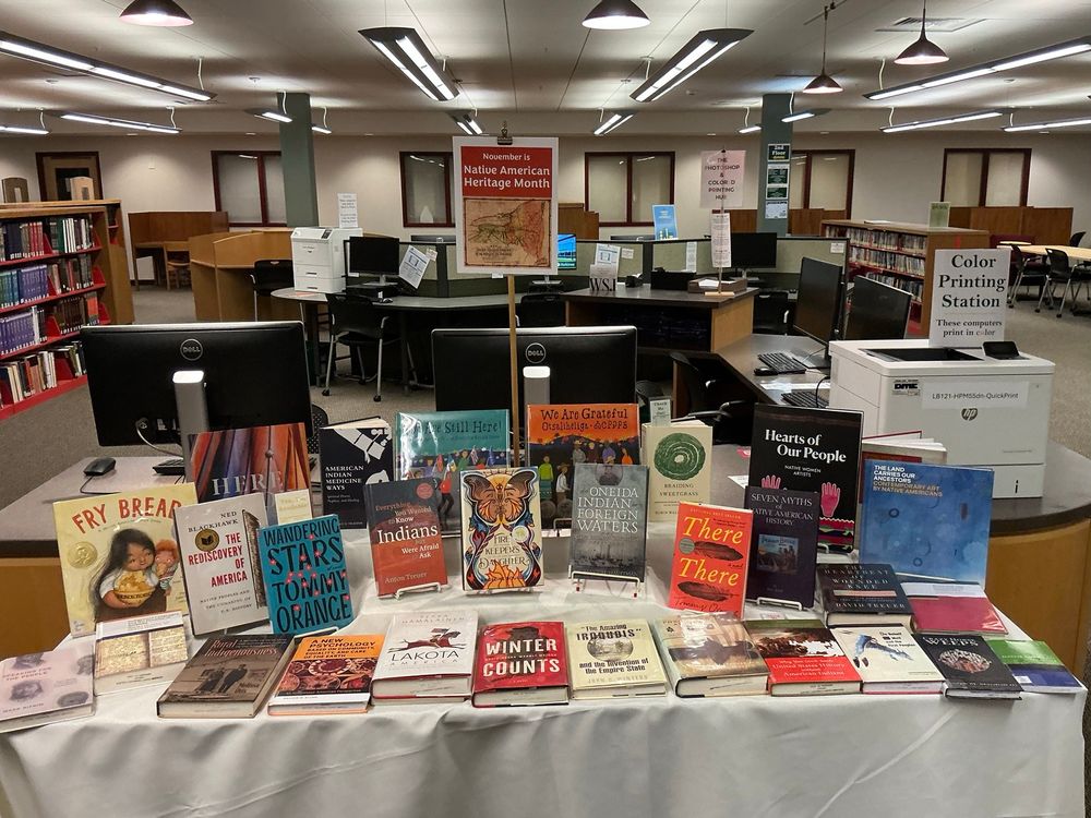 Photo of a book display for Native American Heritage Month. A long table holds many books about Native American history, art, culture, and fiction. 