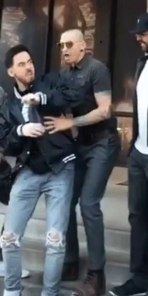 a man in a black jacket is holding another man 's hand