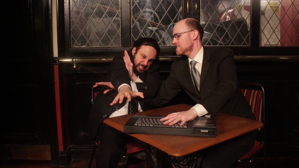 Two men in business suits fight over a 1980s-style computer.