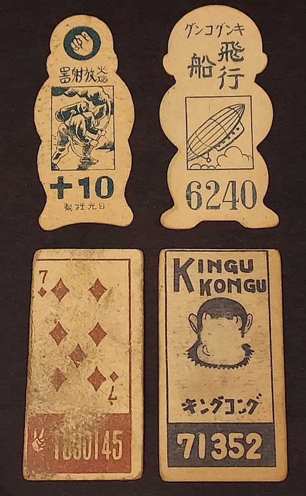 The backs of four vintage Japanese menko cards. The fronts depict King Kong. The backs have various design motifs and feature menko numbers/points used to play games.