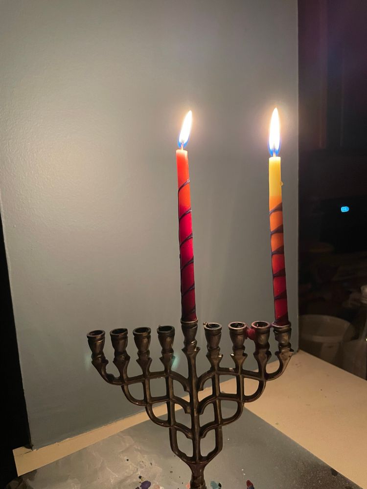 A photo of a small menorah with two candles (including the shamash) lit.