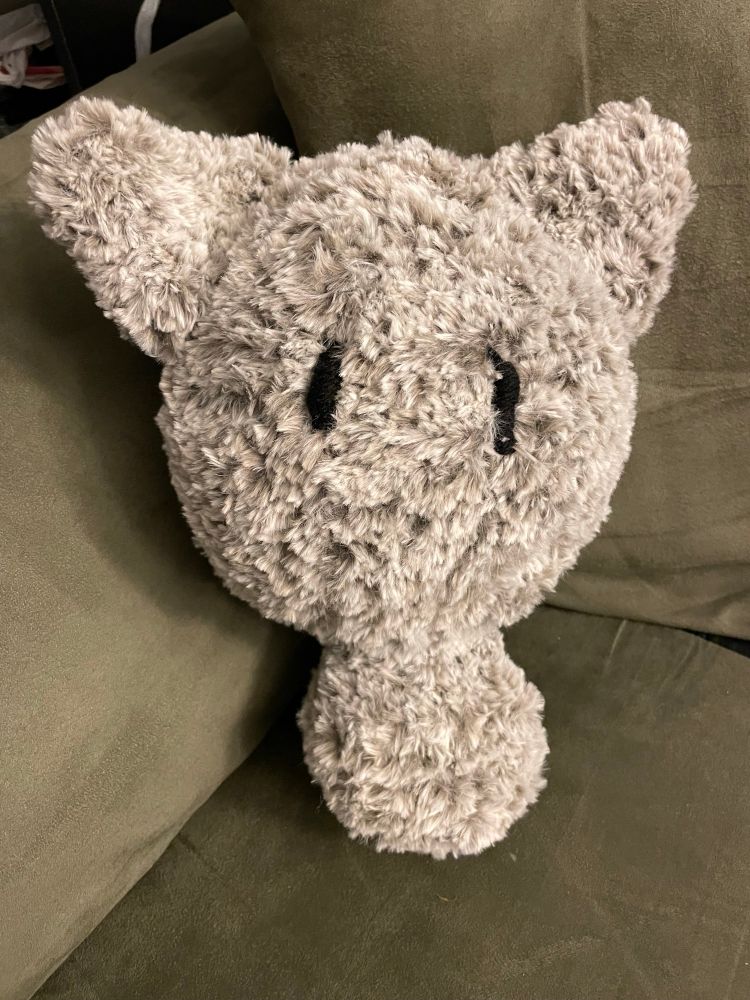 A gray crocheted cat with black eyes. The head is disproportionately large.