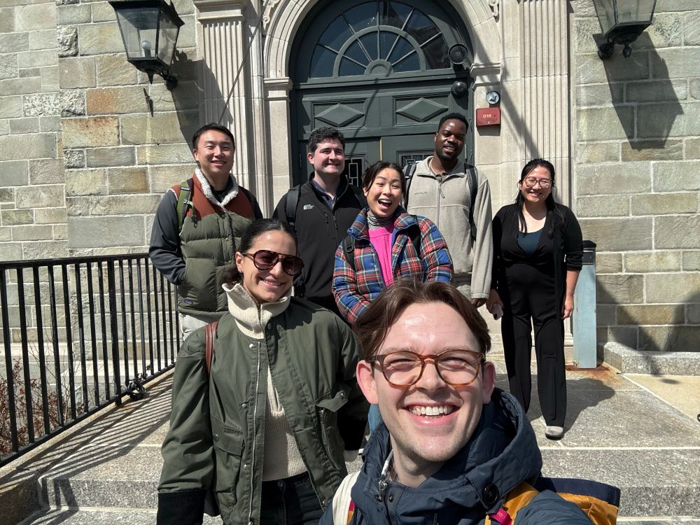 Connor takes a selfie with Isabella, Annika, Ian, Andrew, Batanai, and Pai En on the steps of the Park Hill branch of the Boston Public Library.