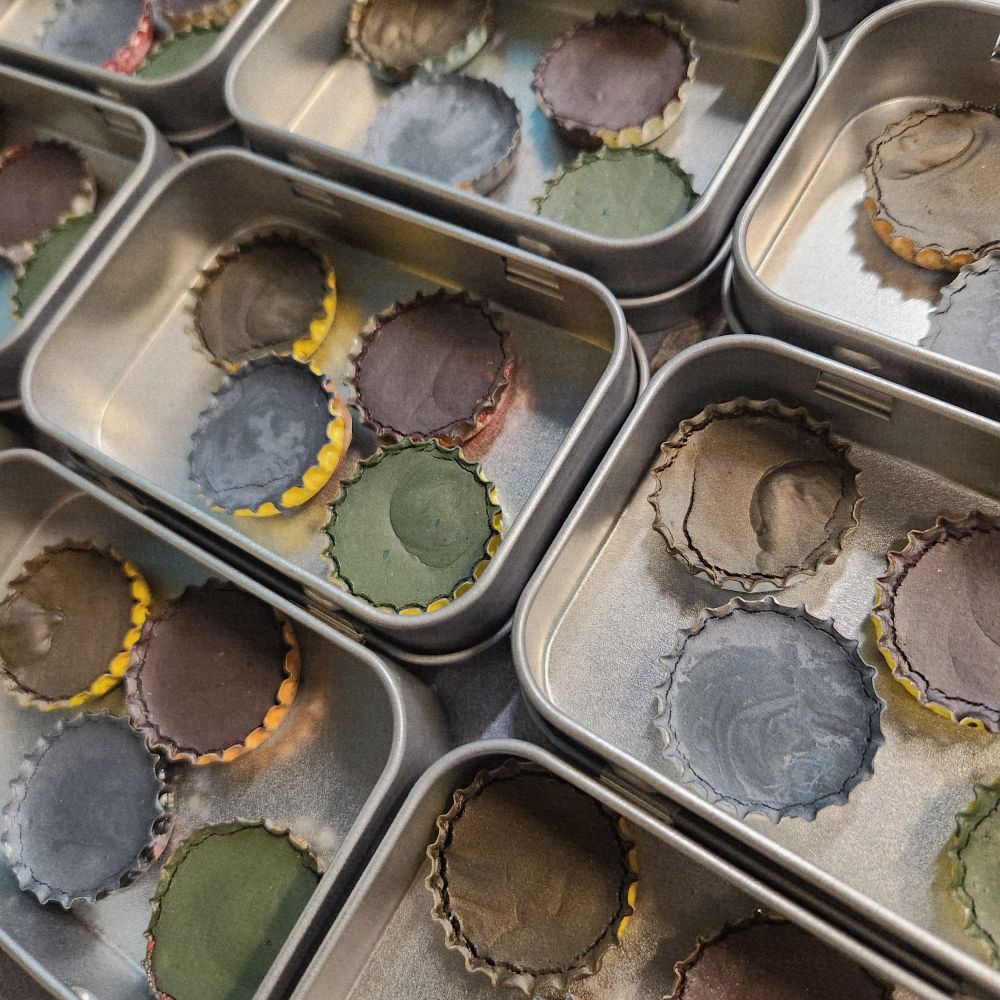 Photo of several open tins of watercolors on display.
