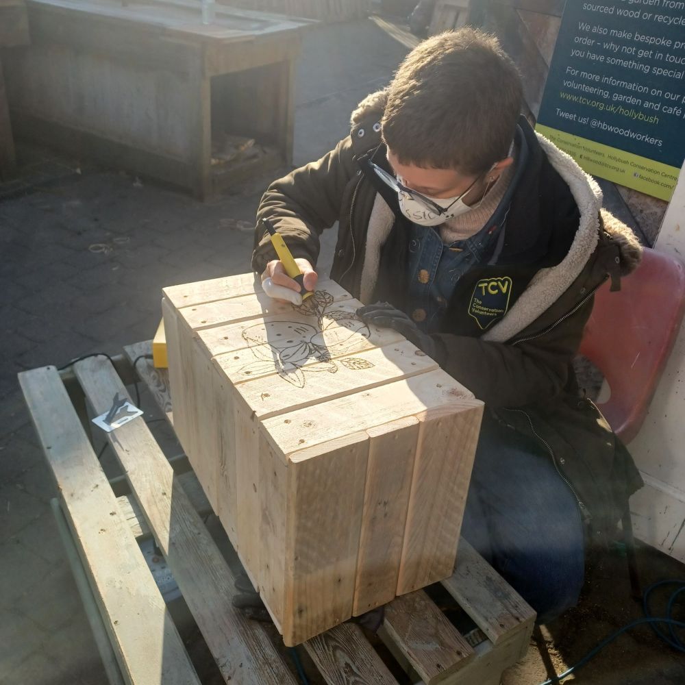 A volunteer pyrographing a potato planter