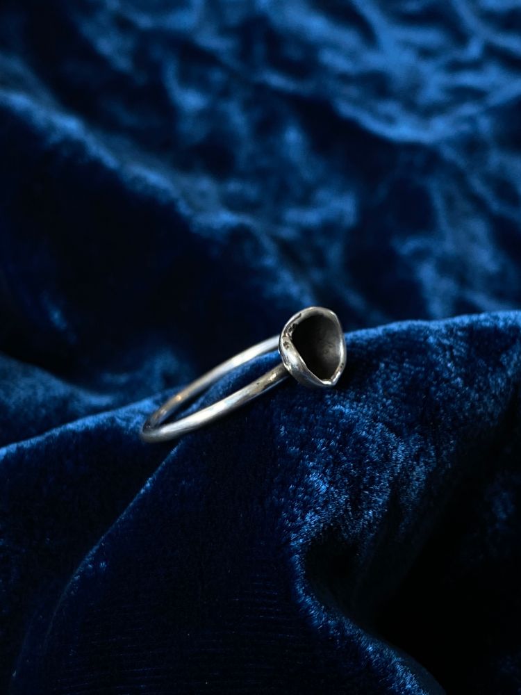 Sterling silver ring with a wee organic cup with blackened inside. Inspired by pixie cup lichen. Displayed on blue velvet.