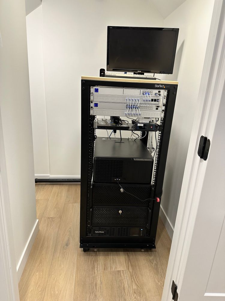 Server rack in a closet with some networking, and a few rack servers with a regular desktop chassis resting on top. 