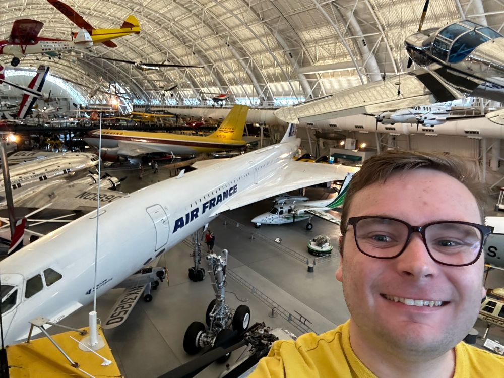 Selfie of the poster, Felix who is standing in front of an Air France Concorde, with other older aircraft in the background.