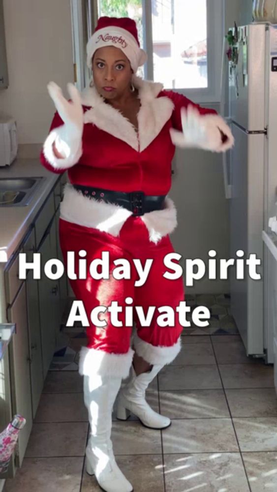 a woman dressed as santa claus is standing in a kitchen