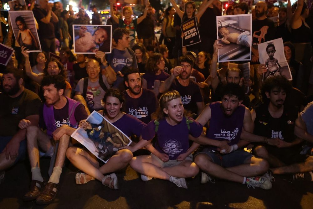 פעילות.ים שלנו יושבות על הכביש עם תמונות של ילדים מזי רעב
