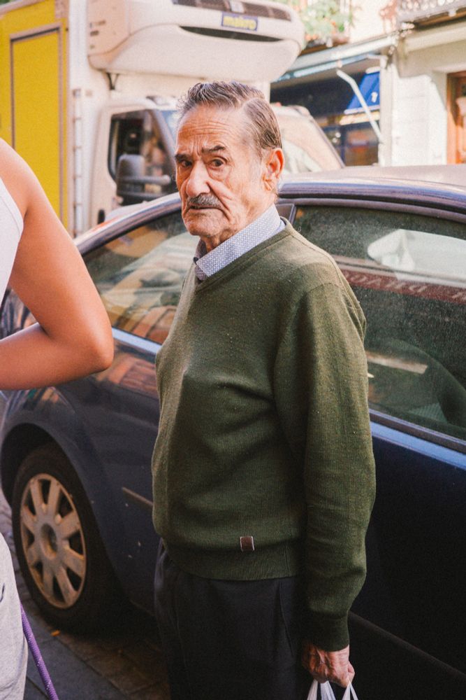 Un señor mayor con un jersey verde mirando a la cámara.