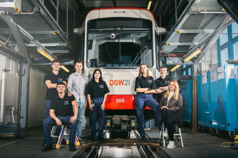 Auszubildende posieren vor einer Stadtbahn