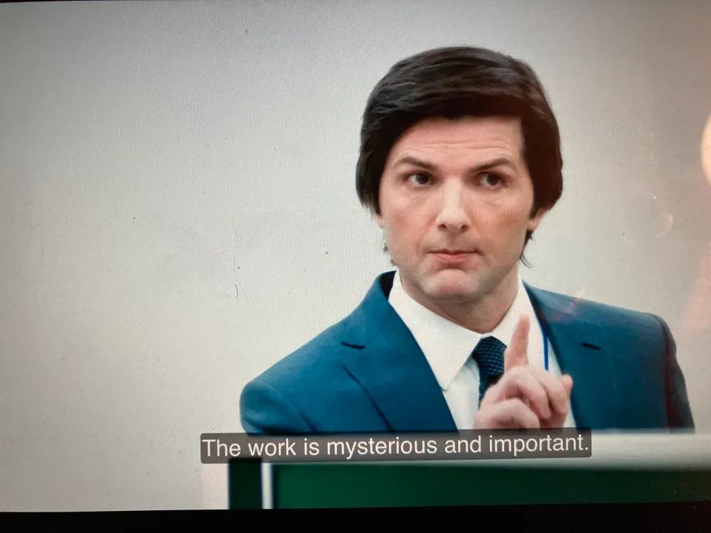Mark from the hit Apple TV show Severance sits behind a desk. Mark is saying "The work is mysterious, and important."