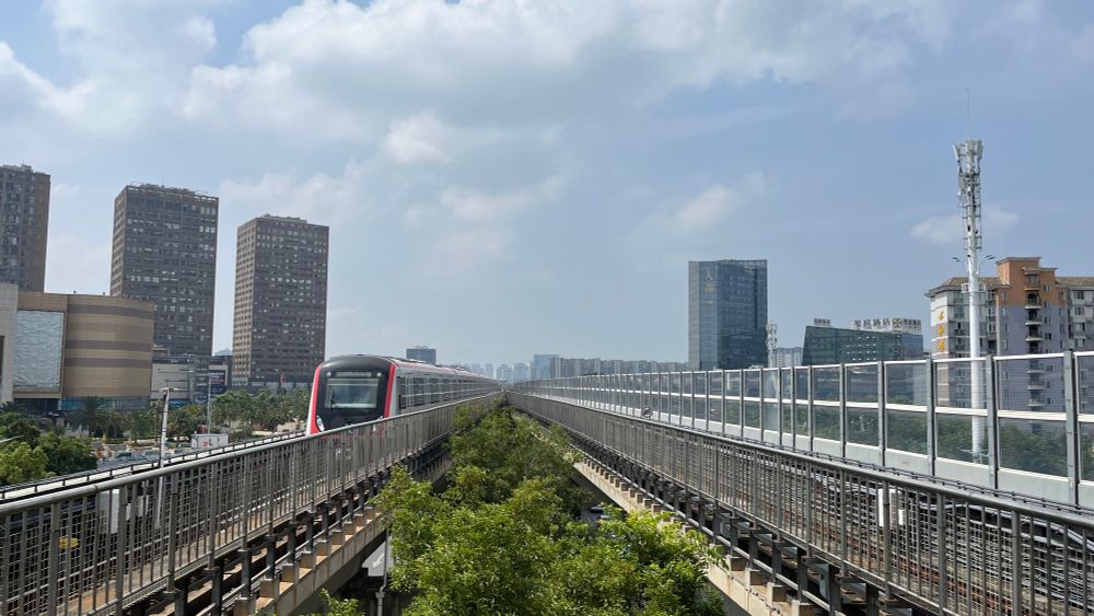 view down an elevated metro viaduct with a train approaching on the left