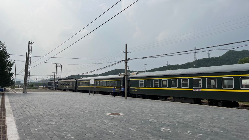 platform at a minor train station with a green skinned chinese regional train in view