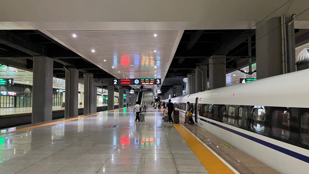 view down a modern high speed rail platform with a high speed train on the right