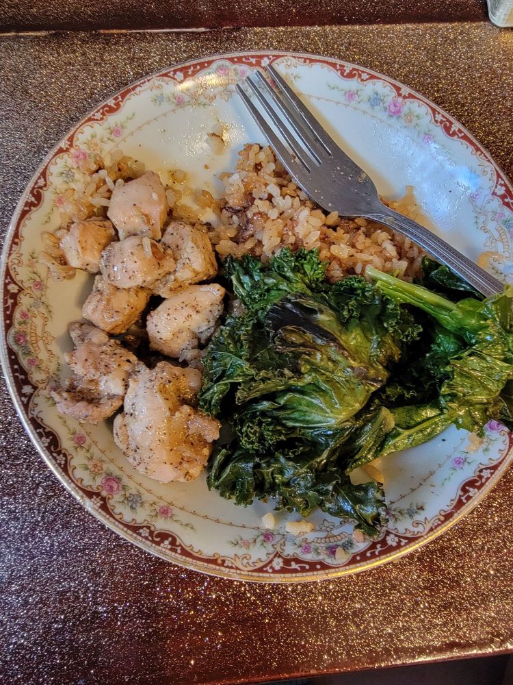 A plate of rice, kale, and pan-fried rabbit