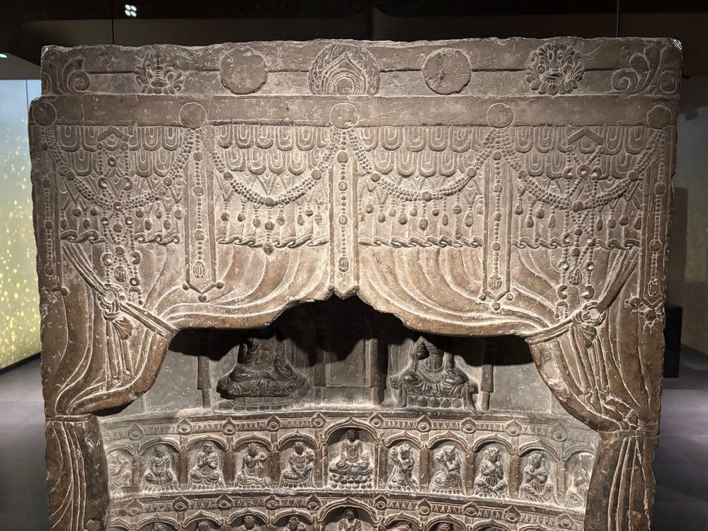 A hanging curtain decorated with festoons and garlands, carved in stone as part of a late sixth century stele.