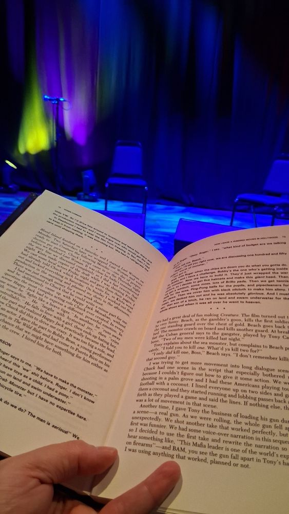 Close-up of an open book with a stage in the background set up for live music
