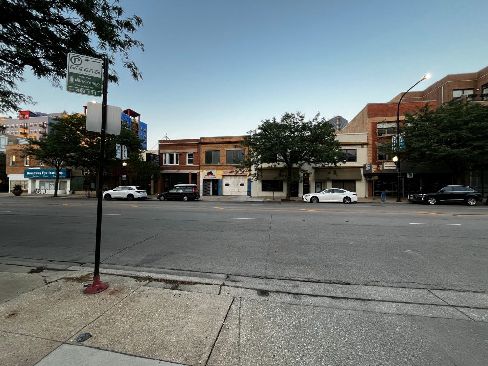 A view of low density commercial developments on Broadway as it cuts through the Edgewater neighborhood in Chicago. Some high density development is visible in the background. A small number of buildings do feature upper floors with apartments. 