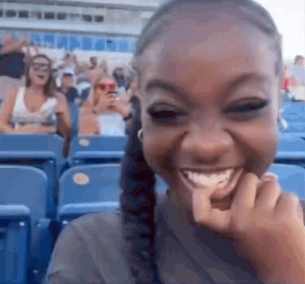 a woman is sitting in a stadium eating a tortilla chip .