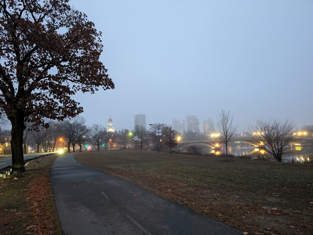 Photo of path along Memorial Drive, with Harvard's Dunster House and the footbridge in the foggy distance.