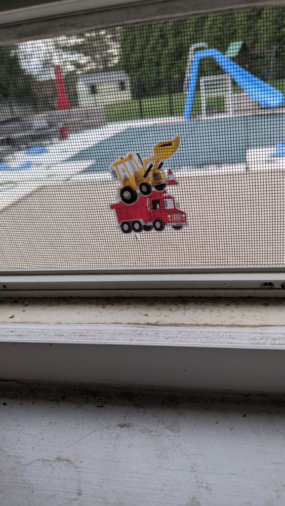 Two construction stickers stuck to a window screen