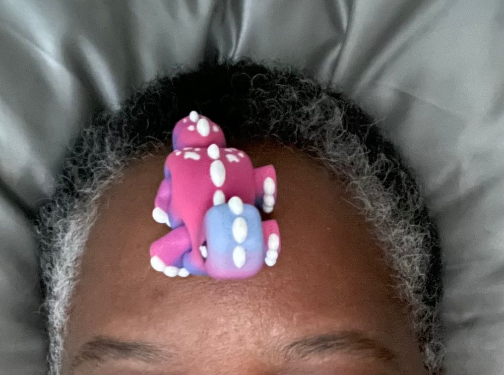 Purple-and-blue dinosaur sitting on my forehead. 