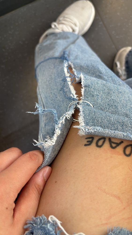 Foto von einem zerrissenen Hosenbein, man sieht Teil von meinem linken Oberschenkel, und meinem tattoo, das Loch der Jeans wird mir einem Metal Ring zusmmengehalten. 