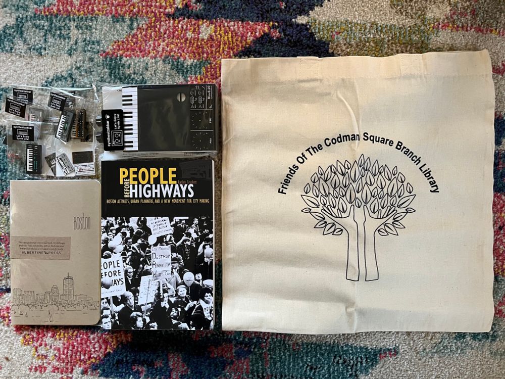 Christmas gifts, Friends Of Codman Square Branch Library tote bag, People Before Highways book, Boston notebook, synthesizer notepad and magnets.