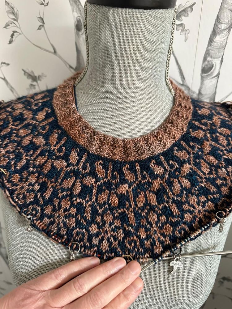 A handknit sweater yoke with scrollwork in a rich brownish gold & navy yarn.