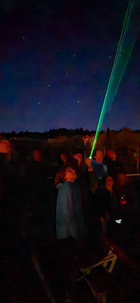 Laser pointer shining into night sky by astronomy guide.