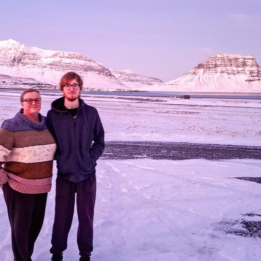 Woman and man in snowy landscape with mountains in background. Grundarfjordur, Iceland.