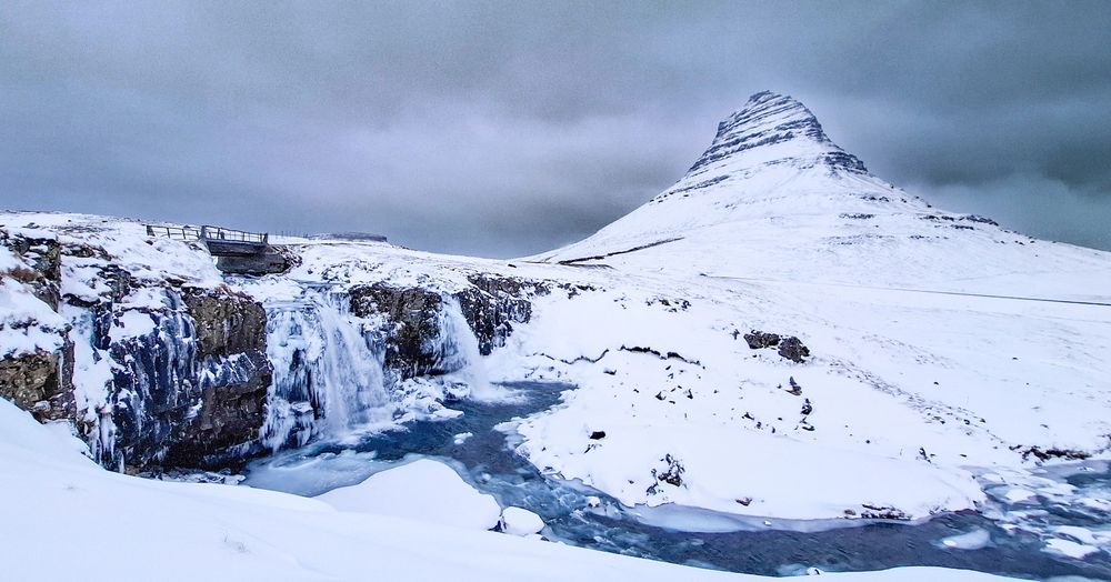 Snow covered mountain and iced up waterfall. Kirkjufellsfossar, Iceland.