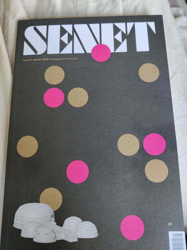 The cover of SENET magazine, showing some gold & pink discs against a black background & a science fiction style habitation dome in the bottom left corner