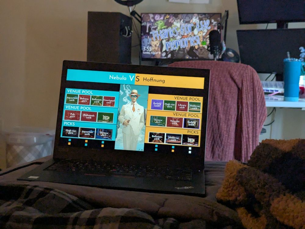 A picture of laptop at the foot of a bed showing a stream of competitive Spy Family in which Nebula is against Hoffnung