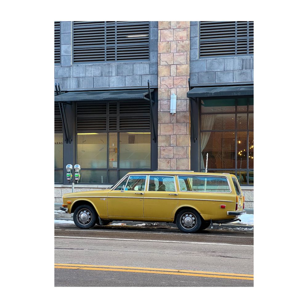 A wonderful old Volvo station wagon. It is this great mustard color. Parked in Downtown Denver on a snowy January afternoon. 

