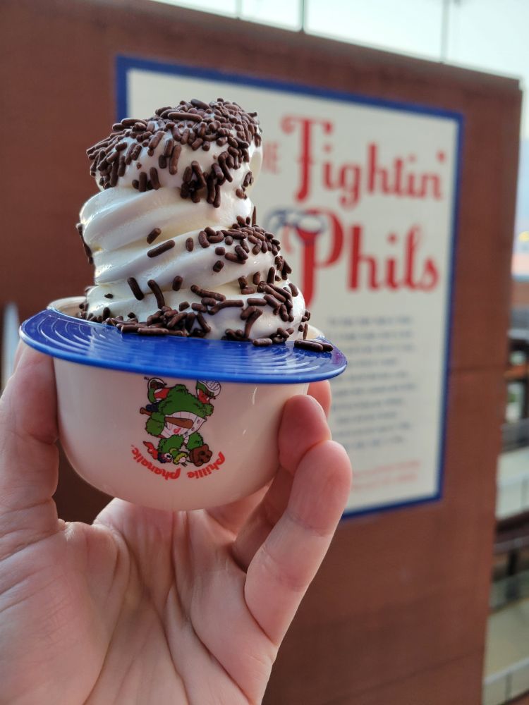 It's soft vanilla ice cream in a plastic miniature batting helmet. The ice cream is covered with chocolate sprinkles. The helmet is white with a blue brim. The crown bears an adorable picture of the Phillie Phanatic.