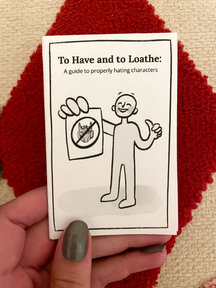 Hand holding a folded minizine titled “To Have and to Loathe: A guide to properly hating characters”. Below it is a simple figure giving a thumbs up and a smile while holding a paper that has Tarn’s head on it with a cross through it.